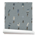 A roll of wallpaper with a pattern of hand-drawn Japanese soldiers carrying various geometric flags, on a blue-gray background.