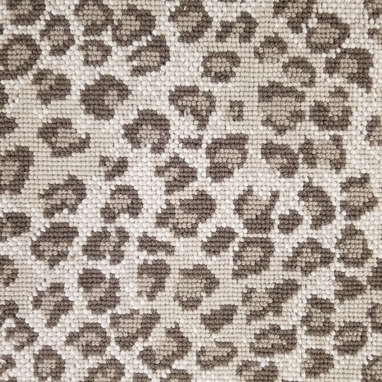 Wool broadloom carpet swatch in a leopard print in tan and brown on a mottled cream field.