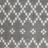 Wool broadloom carpet swatch in a repeating diamond print in white on a gray field.