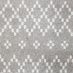 Wool broadloom carpet swatch in a repeating diamond print in white on a light gray field.