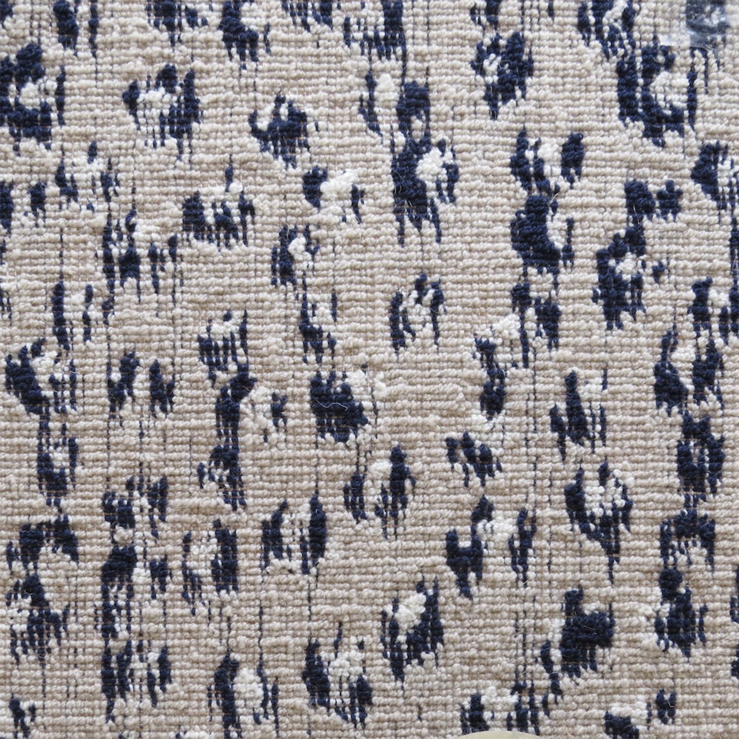 Wool broadloom carpet swatch in a painterly floral pattern in navy and cream on a tan field.