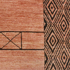 Detail of a high-pile rug in a dusty red with borders of a dense interlocking diamond pattern in black.