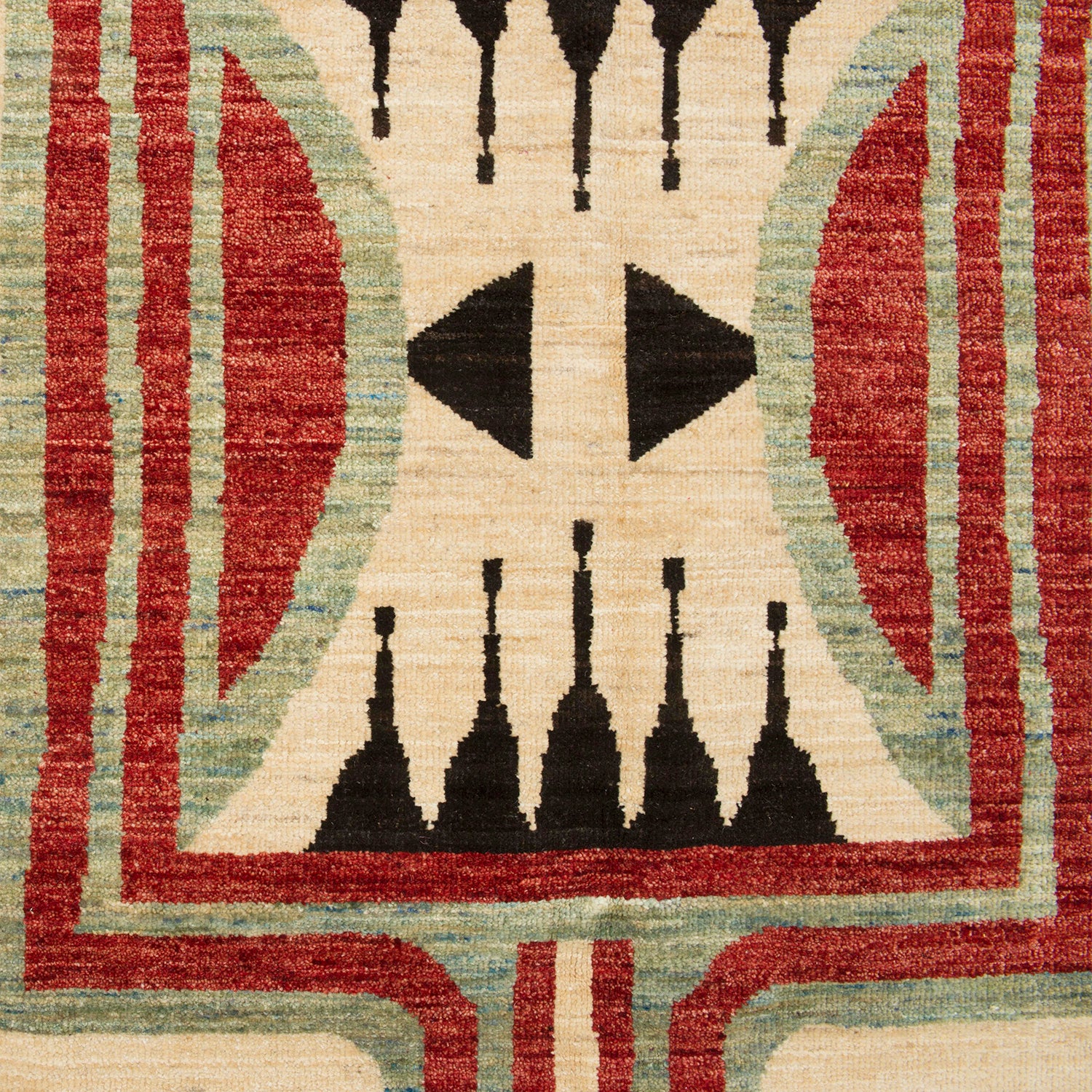 Detail of a high-pile woven rug with a large-scale tribal geometric pattern in shades of red, sage and black on a cream field.