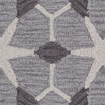 Detail of a wool broadloom carpet swatch in a geometric lattice pattern in cream and charcoal on a gray field.