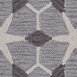 Detail of a wool broadloom carpet swatch in a geometric lattice pattern in cream and charcoal on a gray field.