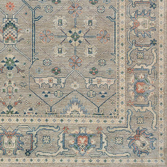 Rug swatch in a repeating geometric print with a floral border in shades of blue-gray, rust and navy.