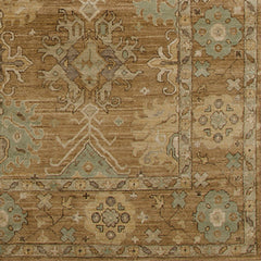 Rug swatch in a repeating geometric print with a floral border in shades of gold, brown and blue-gray.