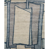 Rectangular rug in a large-scale abstract pattern of overlapping square shapes in shades of navy, tan and brown.