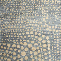 Woven rug swatch in a pattern of many repeating different-sized circles in tan on a blue-gray field.
