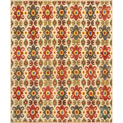 Large rectangular rug in a repeating ikat floral pattern in shades of red, yellow and green on a tan field.
