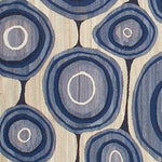 Woven rug swatch in an abstract circular pattern reminiscent of lollipops in shades of blue and gray on a tan field.