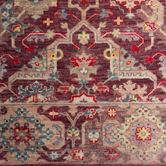 Woven rug swatch in a dense abstract floral pattern with a floral border in shades of pink, red, blue and yellow on a wine field.