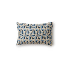A rectangular throw pillow with a repeating pattern of large-scale graphic flowers in blue and navy on a tan background.