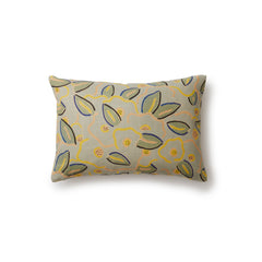 A rectangular throw pillow in a large-scale minimal floral print in shades of yellow, peach and green on a light blue background.