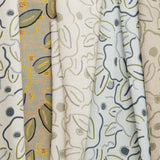 A row of fabric swatches, all in the same large-scale minimal floral print in different colorways with tan, cream and white fields.