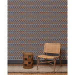 Wood and woven chair, brown stool and rug in front of wallpaper with a pattern of vertical stripes of light brown, navy blue and dashes of rust red and white, hover