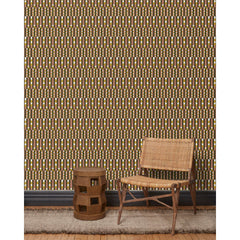 Wood and woven chair, brown stool and rug in front of wallpaper with a pattern of vertical stripes of pink, warm olive green and dashes of yellow and white, 