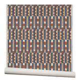 Wallpaper roll with a pattern of vertical stripes of light brown, navy blue and dashes of rust red and white.