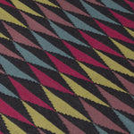 Detail of the Trio Rug in Jewel, a stacked triangle pattern with black, ruby red, blue, heather purple and yellow. 