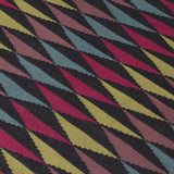 Detail of the Trio Rug in Jewel, a stacked triangle pattern with black, ruby red, blue, heather purple and yellow. 