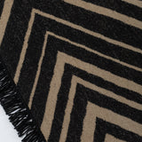 Detail of the Vertical Zig-Zag Rug in Onyx-Sandstone, a zig zag pattern in mixed widths in black and taupe with a fringed edge. 