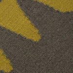 Detail of the Waver Rug in Cardinal Yellow, a dark taupe field with a yellow flame stitch border. 