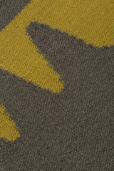 Detail of the Waver Rug in Cardinal Yellow, a dark taupe field with a yellow flame stitch border. 