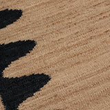 Detail of the Waver Rug in Jet Black, a strated ecru field with a black flame stitch border. 