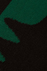 Detail of the Waver Rug in Modernist Green, a solid black field with a green flame stitch border. 