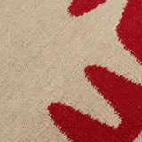 Detail of the Waver Rug in Pillbox Red, a solid Ivory field with a red flame stitch border. 