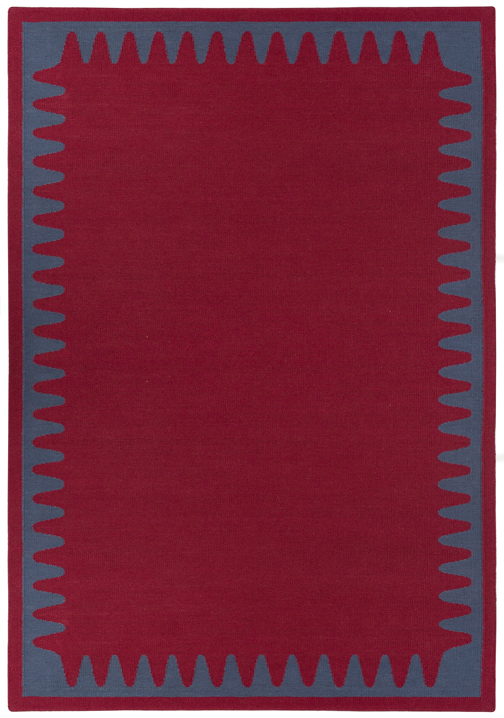 Waver Rug in Queensdown Red, a solid red field with a blue flame stitch border. 