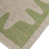 Detail of the Waver Rug in Sage, a strated taupe field with a sage green flame stitch border. 