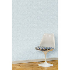 A white swivel chair in front of a wall papered in a large-scale repeating leaf print in white on a light blue watercolor background.
