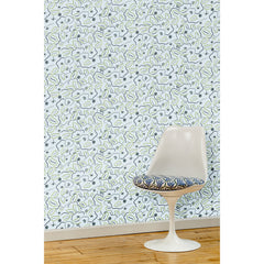 A white swivel chair in front of a wall papered in a large-scale minimal floral print in shades of navy, gray and green on a light blue background.
