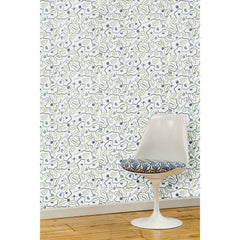  A white swivel chair in front of a wall papered in a large-scale minimal floral print in shades of navy, blue-gray and green on a white background.