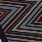 Detail of the To The Point Rug in Hessonite-Garnet-Slate, a zig zag pattern in red, blue coral with black, with a black fringed edge. 