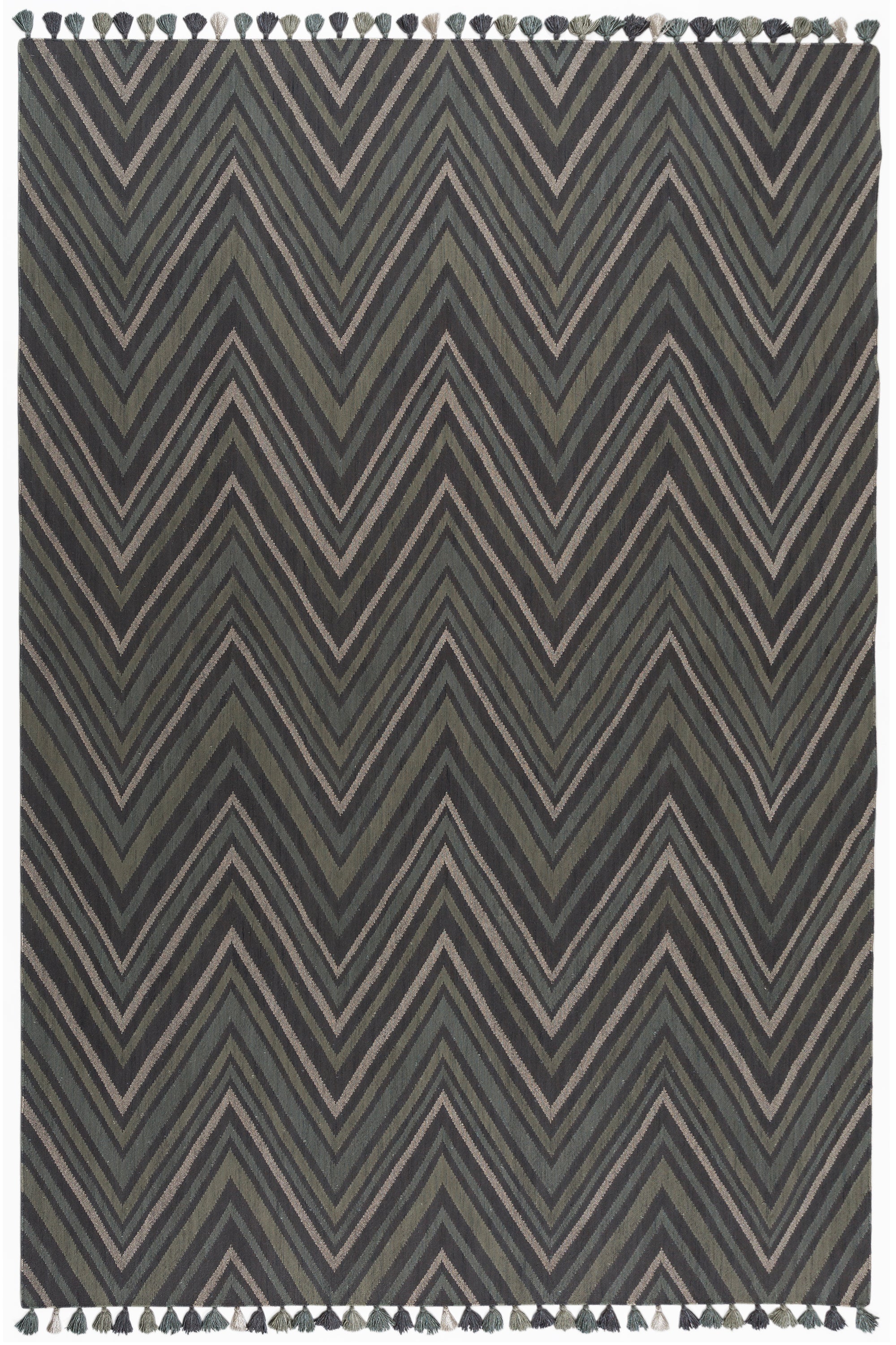 Full size To The Point Rug in Pyrite-Metallic, a zig zag pattern in dark greens, metallic ecru and black, with a mulit color tasseled edge. 
