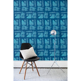 A chair and floor lamp in front of a wall papered in a large-scale pattern of abstract blue watercolor shapes on a navy background.