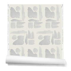 Partially unrolled wallpaper in a large-scale pattern of abstract gray watercolor shapes on a cream background.