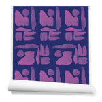 Partially unrolled wallpaper in a large-scale pattern of abstract purple watercolor shapes on a dark purple background.