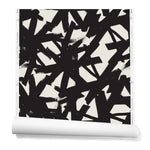 Partially unrolled roll of wallpaper in a bold black brushtroke pattern on a white background.