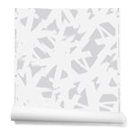 Partially unrolled roll of wallpaper in a bold white brushtroke pattern on a light gray background.