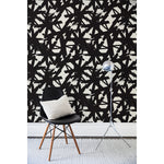 Chair and floor lamp in front of a wall papered in a bold black brushtroke pattern on a white background.