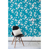 Chair and floor lamp in front of a wall papered in a bold turquoise brushtroke pattern on a white background.
