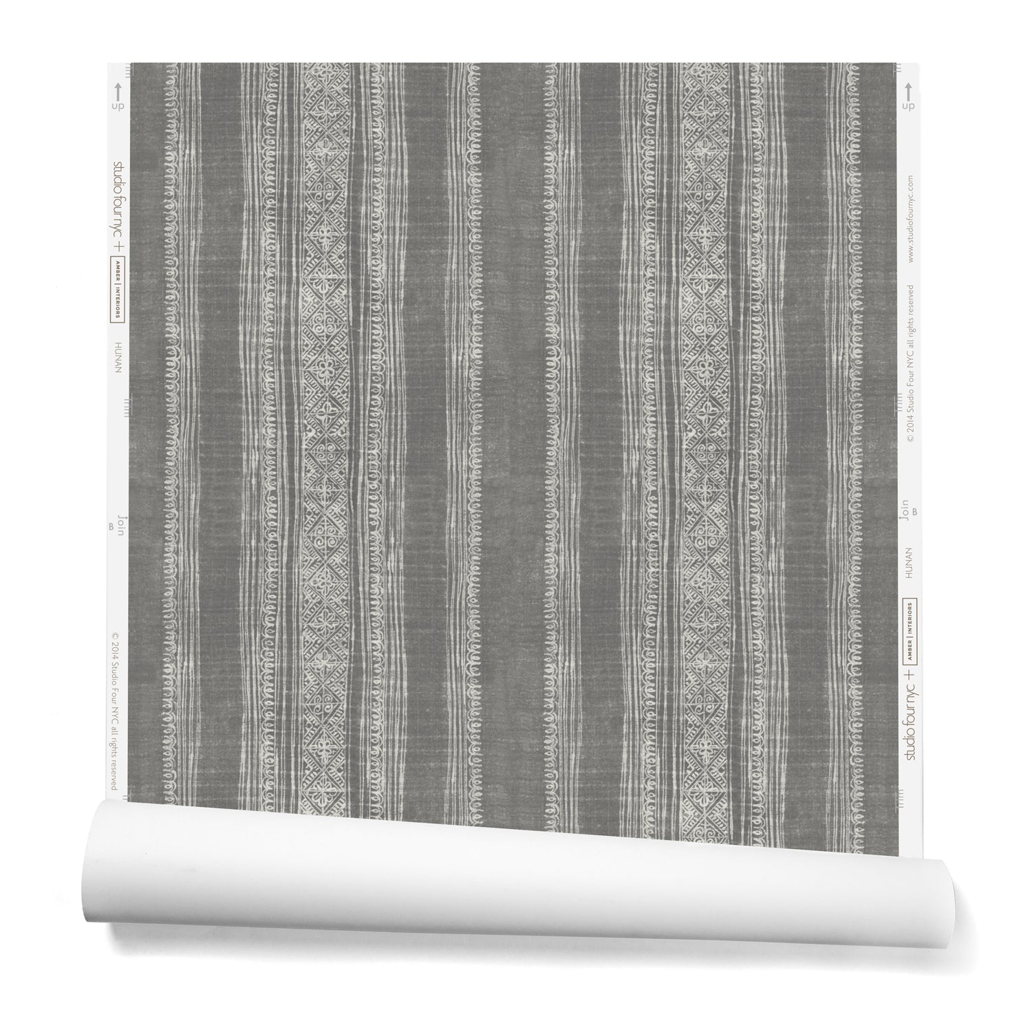 A partially unrolled roll of wallpaper in a striped pattern of intricate white lines over a washed gray background.