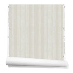 A partially unrolled roll of wallpaper in a striped pattern of intricate white lines over a washed beige background.