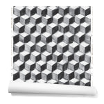 Partially unrolled wallpaper in a hand-painted tumbling block pattern in black and gray on a white background.