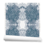 Partially unrolled wallpaper in a dense hand-drawn symmetrical pattern in shades of blue on a white background.