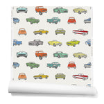 A roll of wallpaper with a linear pattern of illustrated retro cars in a variety of bright colors on a cream background.