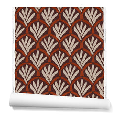 A hanging roll of wallpaper with a repeating Moroccan-inspired scallop pattern in white and red on a maroon background.
